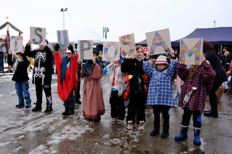 Děti drží barevné papíry s písmenky, která dohromady tvoří slovo MASOPUST.